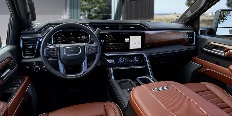 2026 GMC Sierra 2500 interior showcasing a digital driver display, GMC-branded steering wheel, and a large vertical touchscreen infotainment system within a sleek, modern dashboard design.