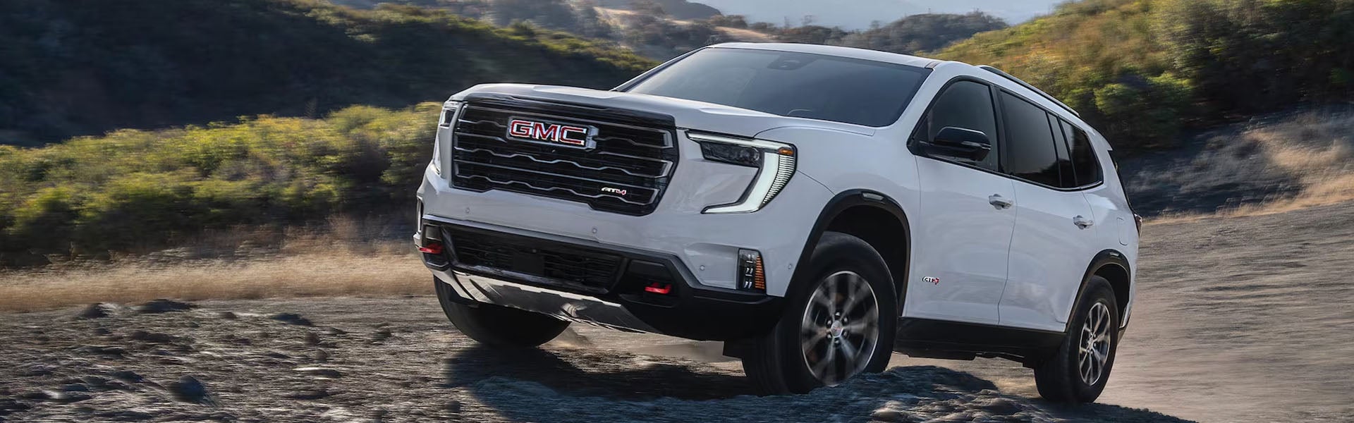 2026 GMC Acadia white SUV driving on an off-road trail