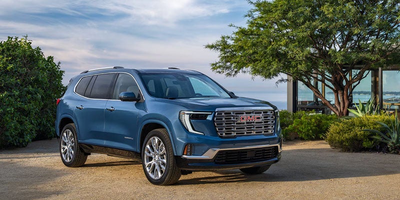 2026 GMC Acadia blue SUV parked outdoors near trees